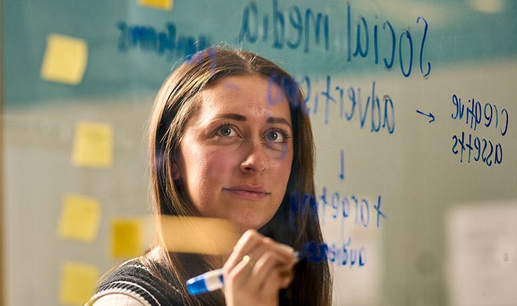 Woman brainstorming on a clear board